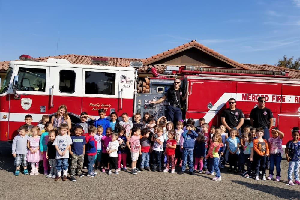 Children gathered with community helpers during an educational visit.